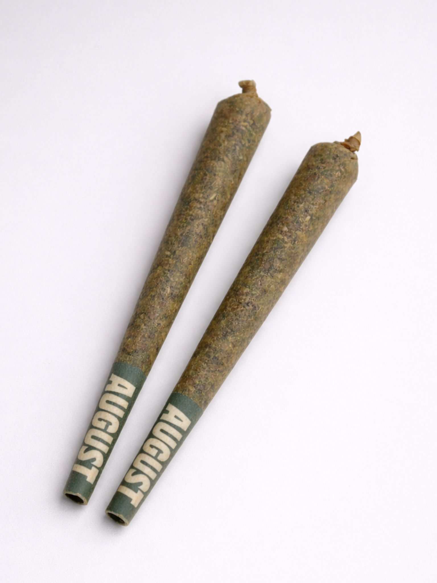 Two king-sized THCa prerolls with green filter tips on a light gray backdrop | August Cannabis Club